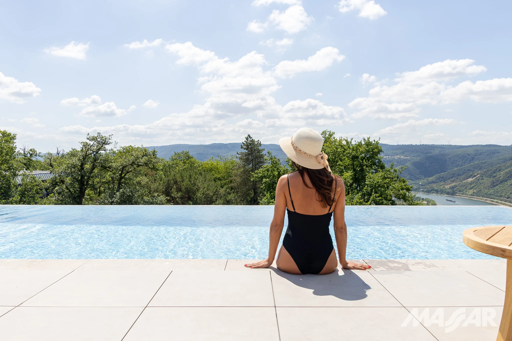 Hotelgast am Infinity-Pool mit Blick über die bewaldete Landschaft